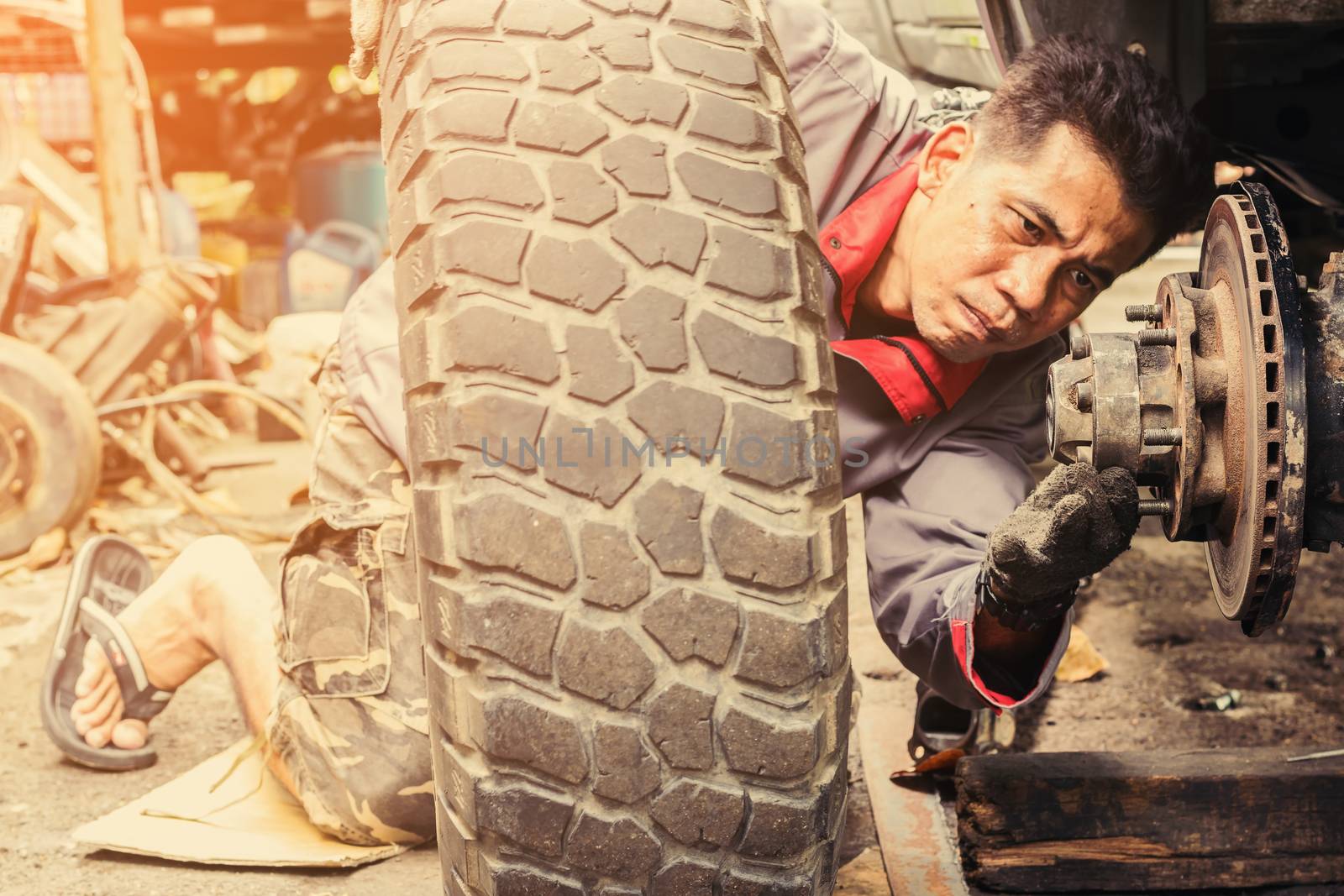 The technician is putting the car's wheels back into place after removing them to repair the brakes.