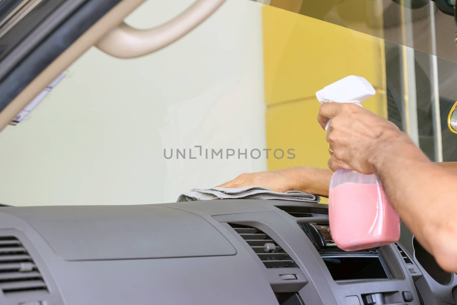 Cleaning staff is using a varnish and microfiber cloth to clean the interior of the car, concept for car care industry.