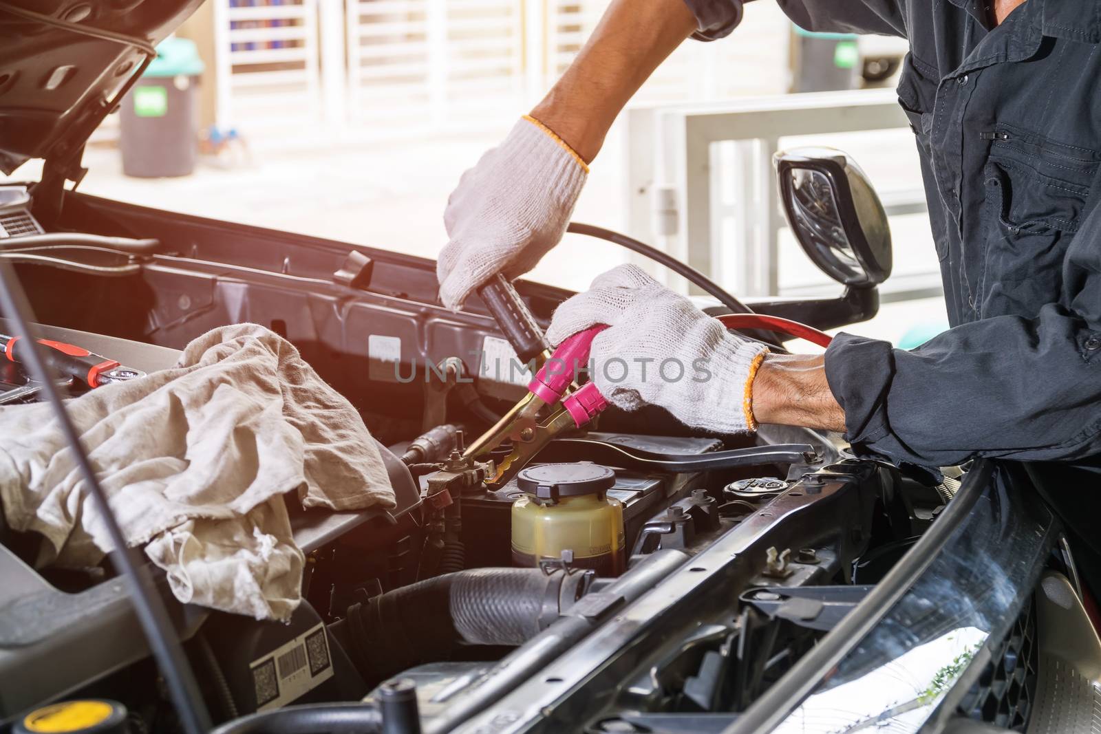 Technicians are using wires to plug the car's battery to charger , Automotive industry and garage concepts.