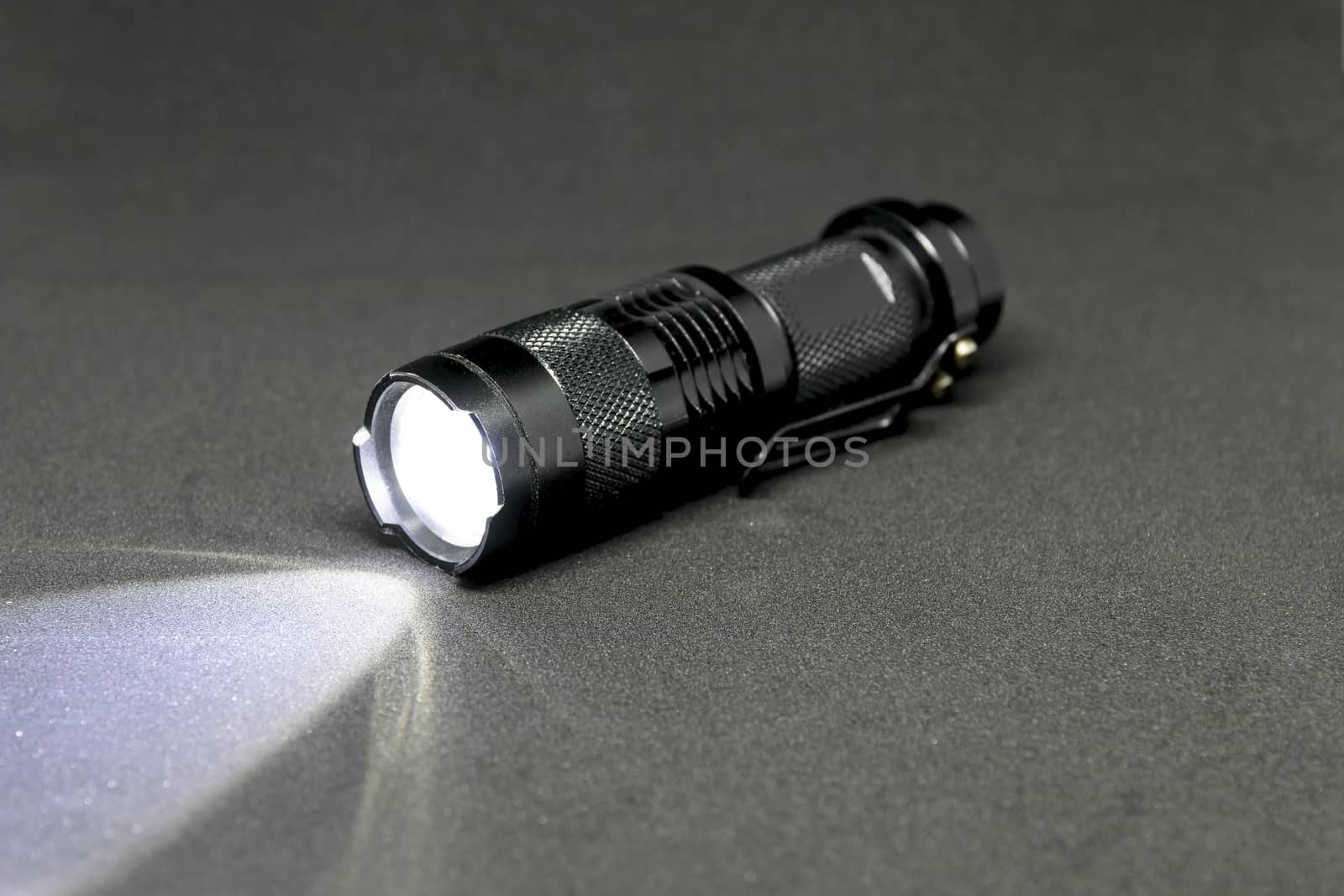 Closeup pocket LED flashlight on dark background.