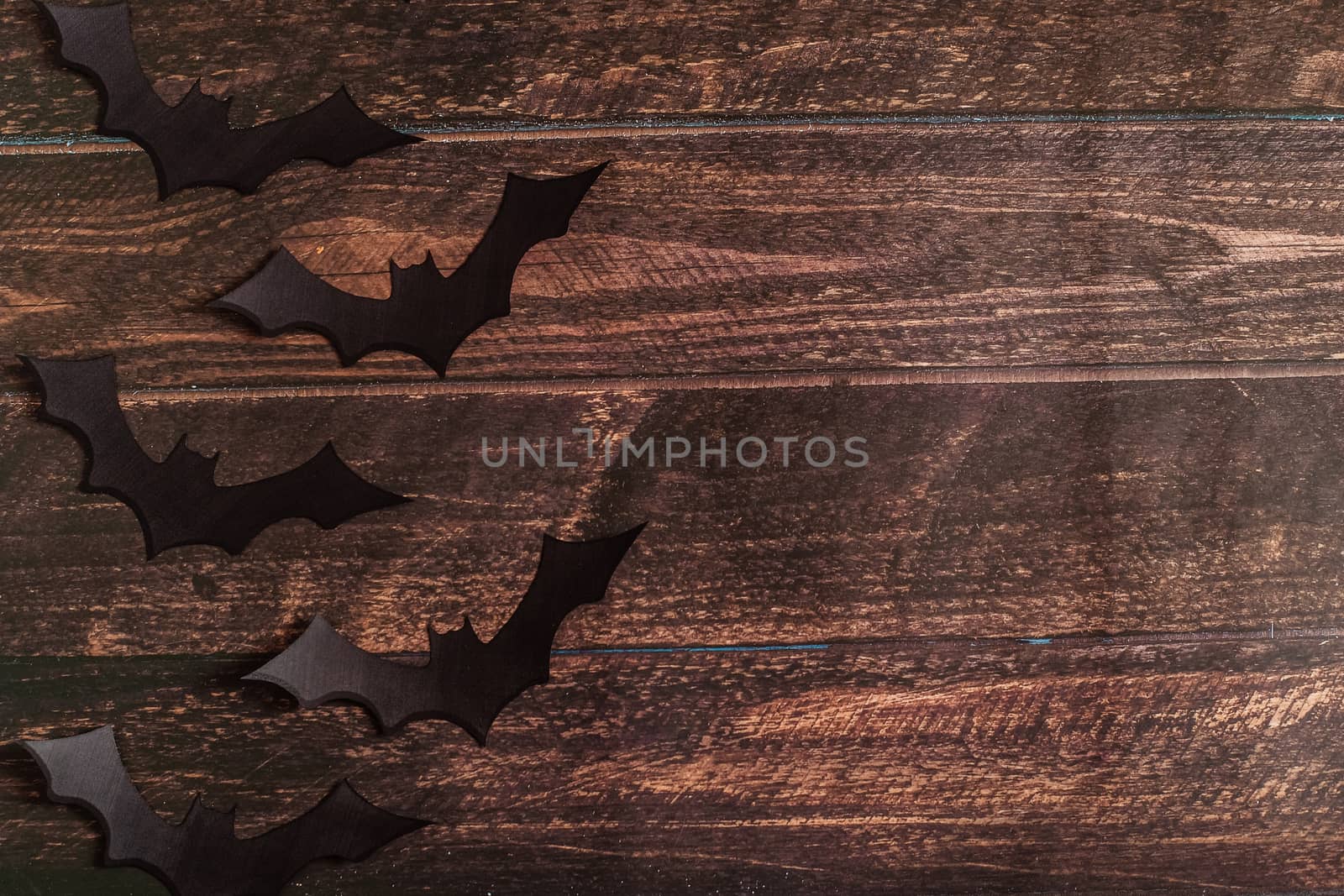 black paper bat silhouettes on brown wooden background, Halloween concept, top view, space for text, Flat lay for your design.