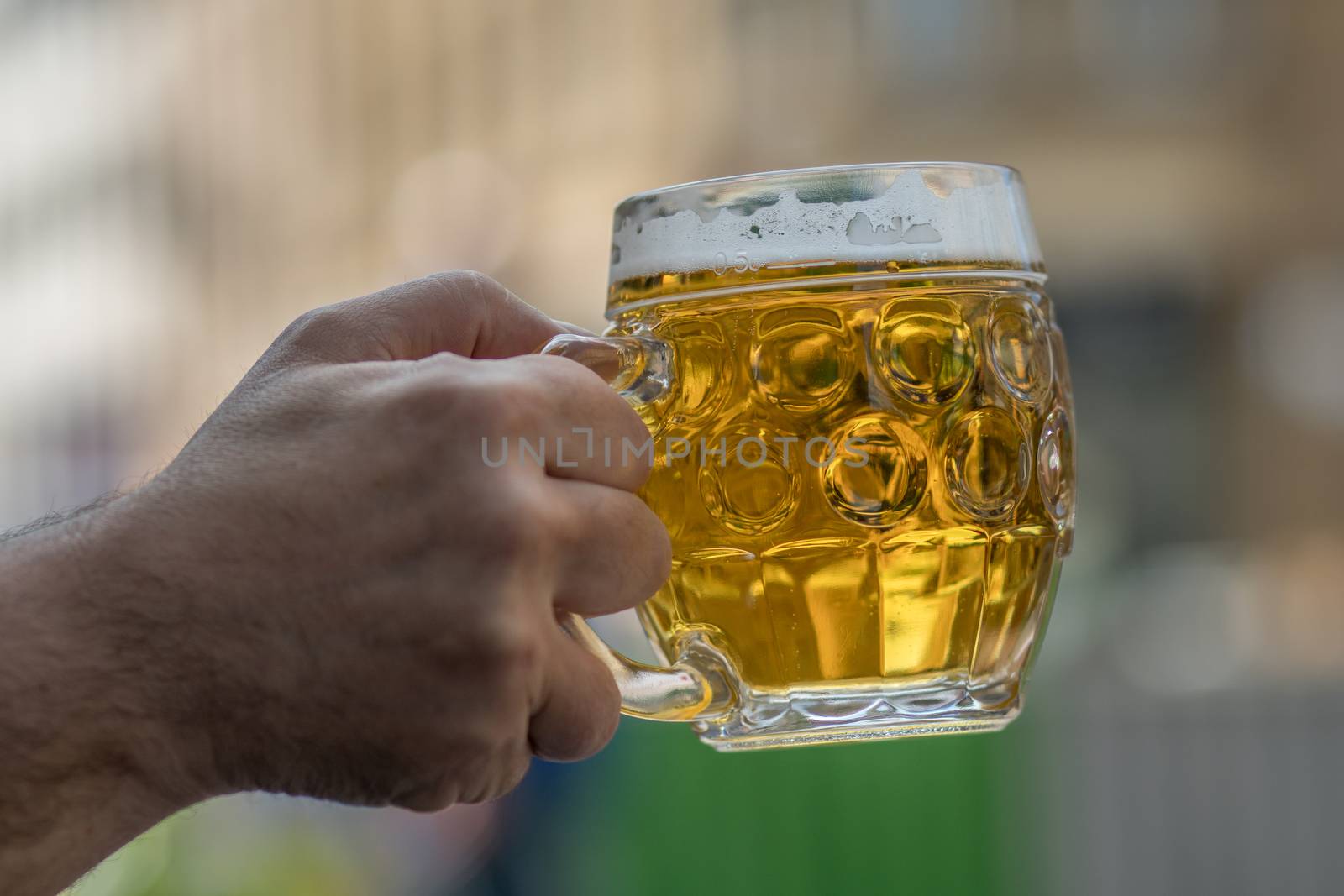 Chilled drink Mug of cold beer. Beer addiction. Alcohol consumption. Harmful addiction. An outstretched hand holds a glass of beer.