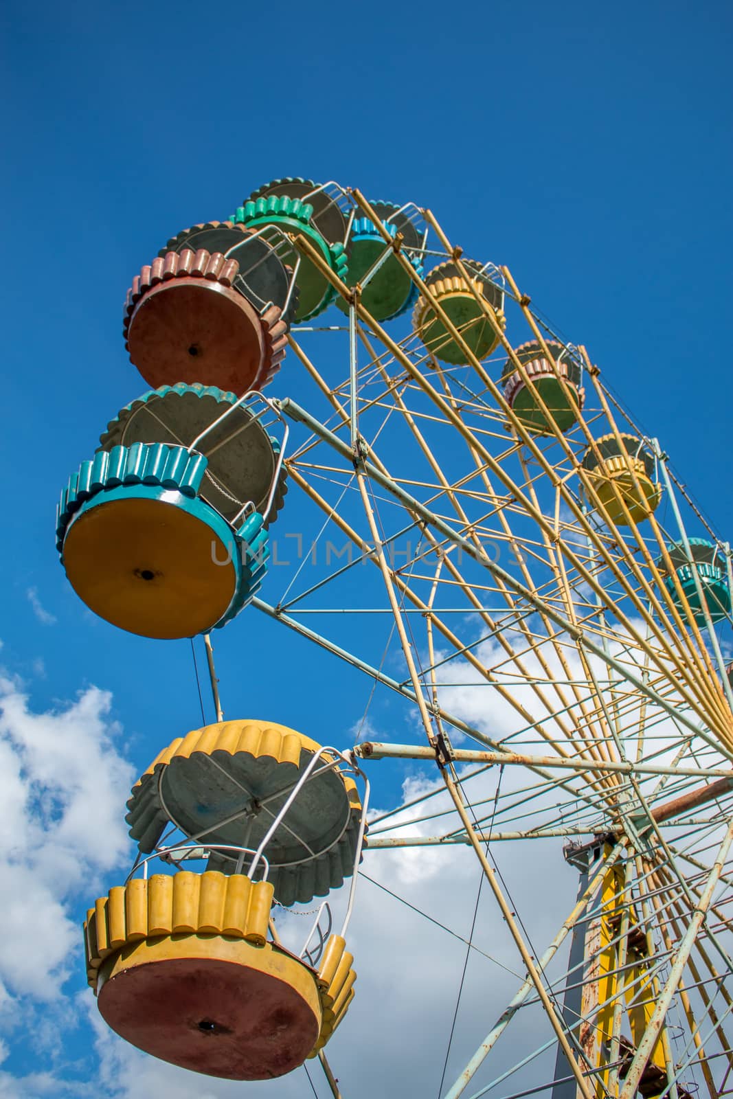 Old fashioned ferris wheel. Rusty ferris wheel. Panoramic wheel. Old carousel in an undeveloped country. Not a safe attraction.