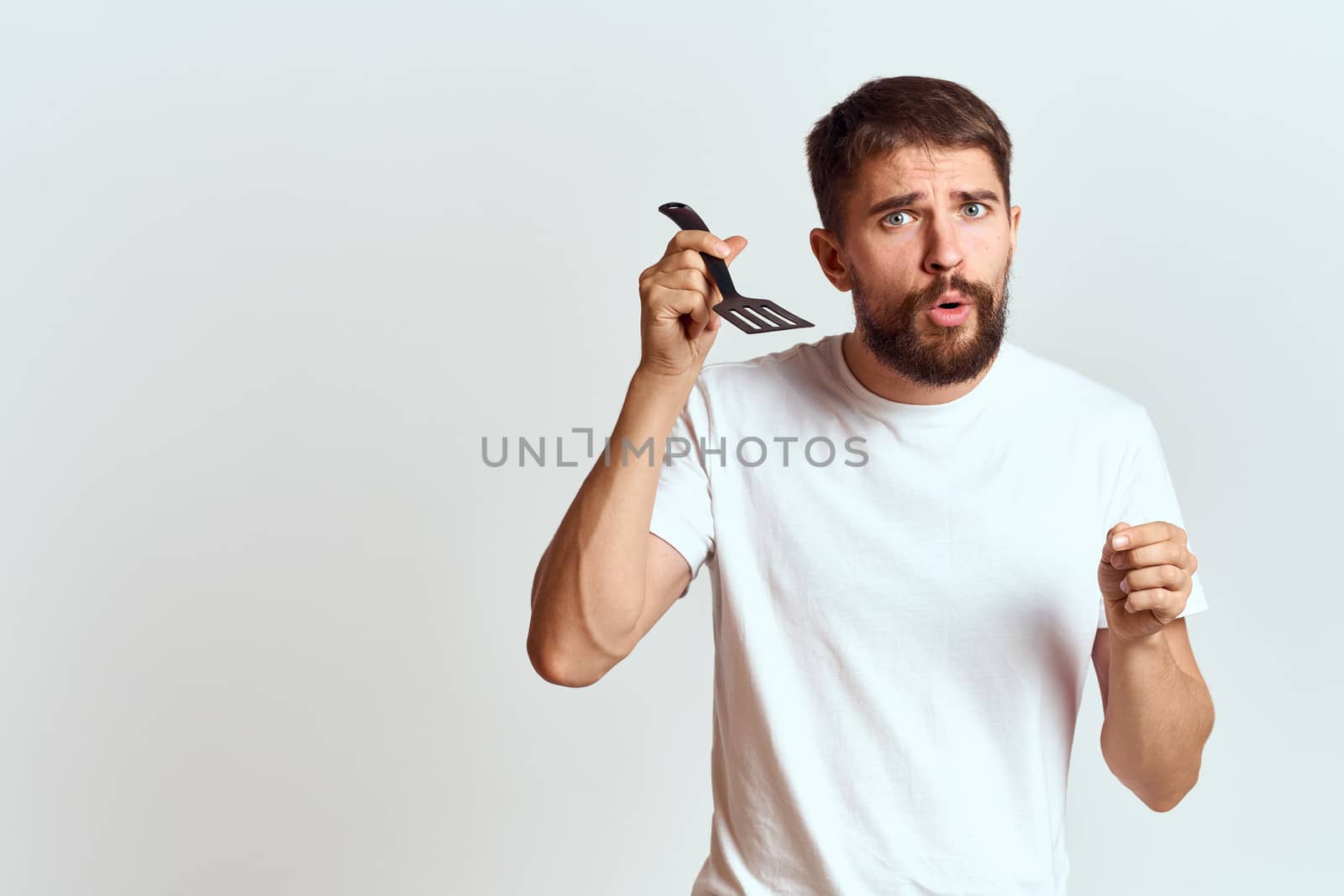 man with cooking shovel and white t-shirt close-up cropped view emotion gesturing with hand. High quality photo