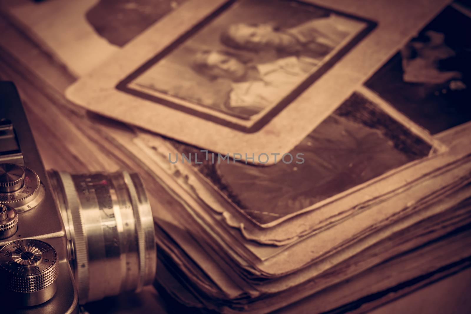 Photo of an old shabby family photo album. Old camera model on a background of an album with photos. Toned photo. Photo album with photos from the last century.
