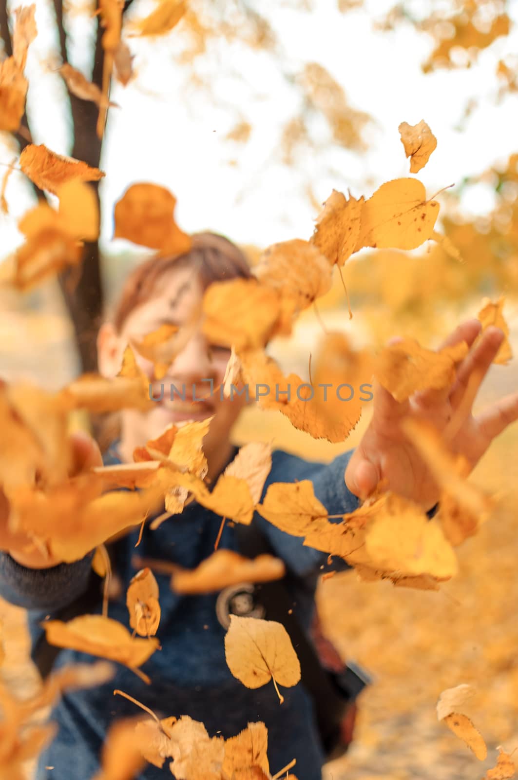 happy child playing with leaves in autumn in the forest. Girl Throwing Dry Leaves into Camera.Seasonal Outdoor Activities with Children. Capture lifestyle on a walk. by Alla_Morozova93