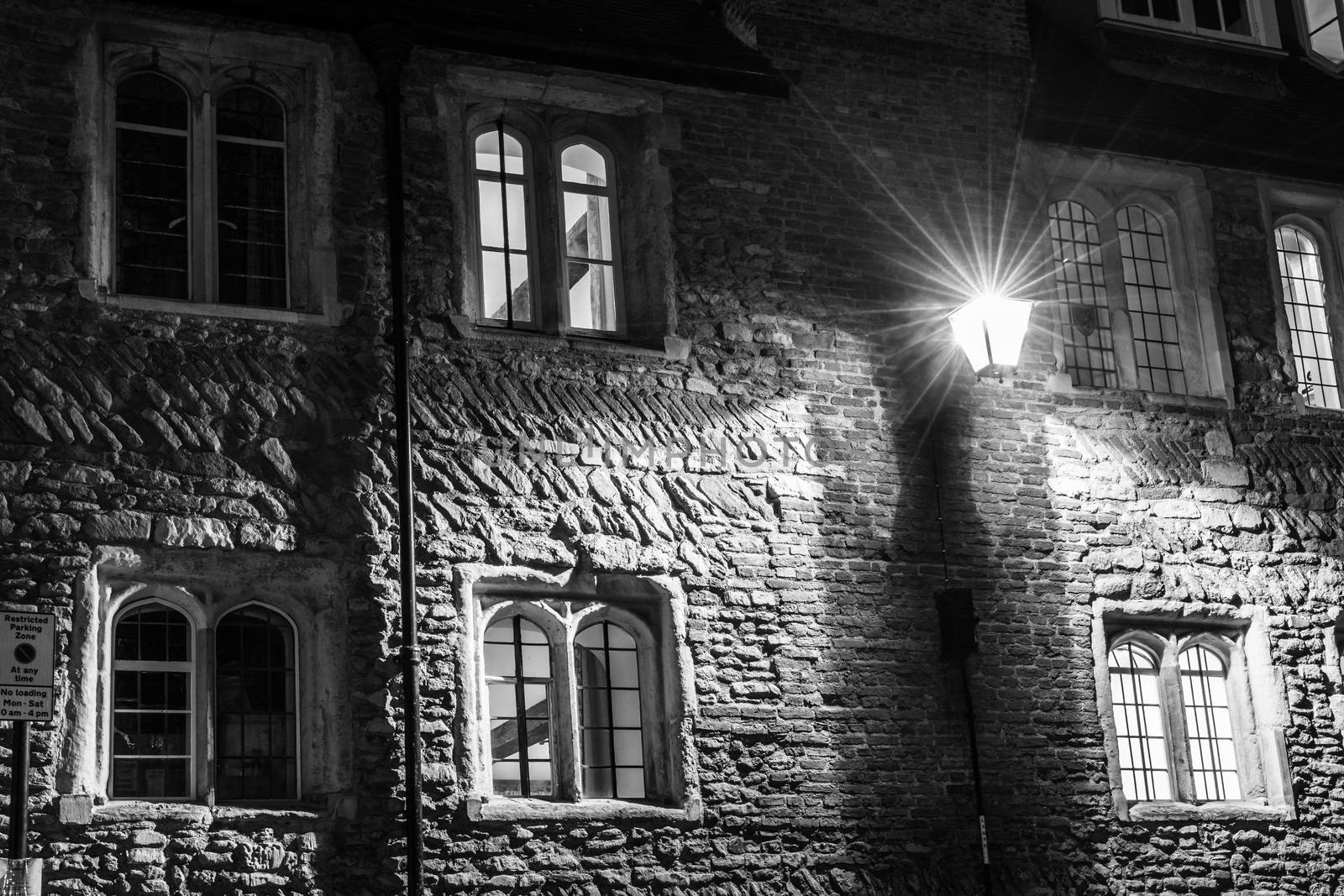 Illuminated windows and brick wall in Trinity Lane at night, Cambridge, United Kingdom