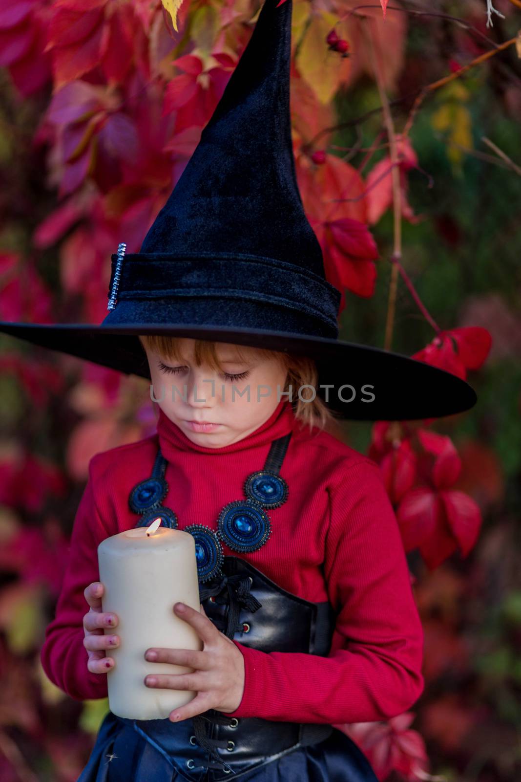 Little girl dressed as a witch holding a candle on a halloween party