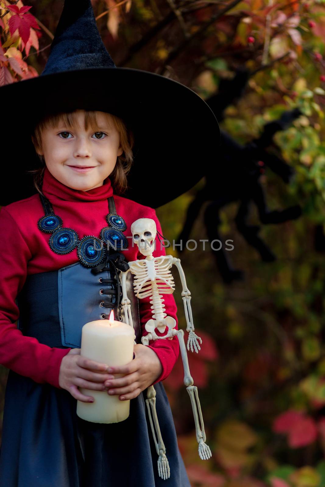 Little girl dressed as a witch holding a candle on a halloween party