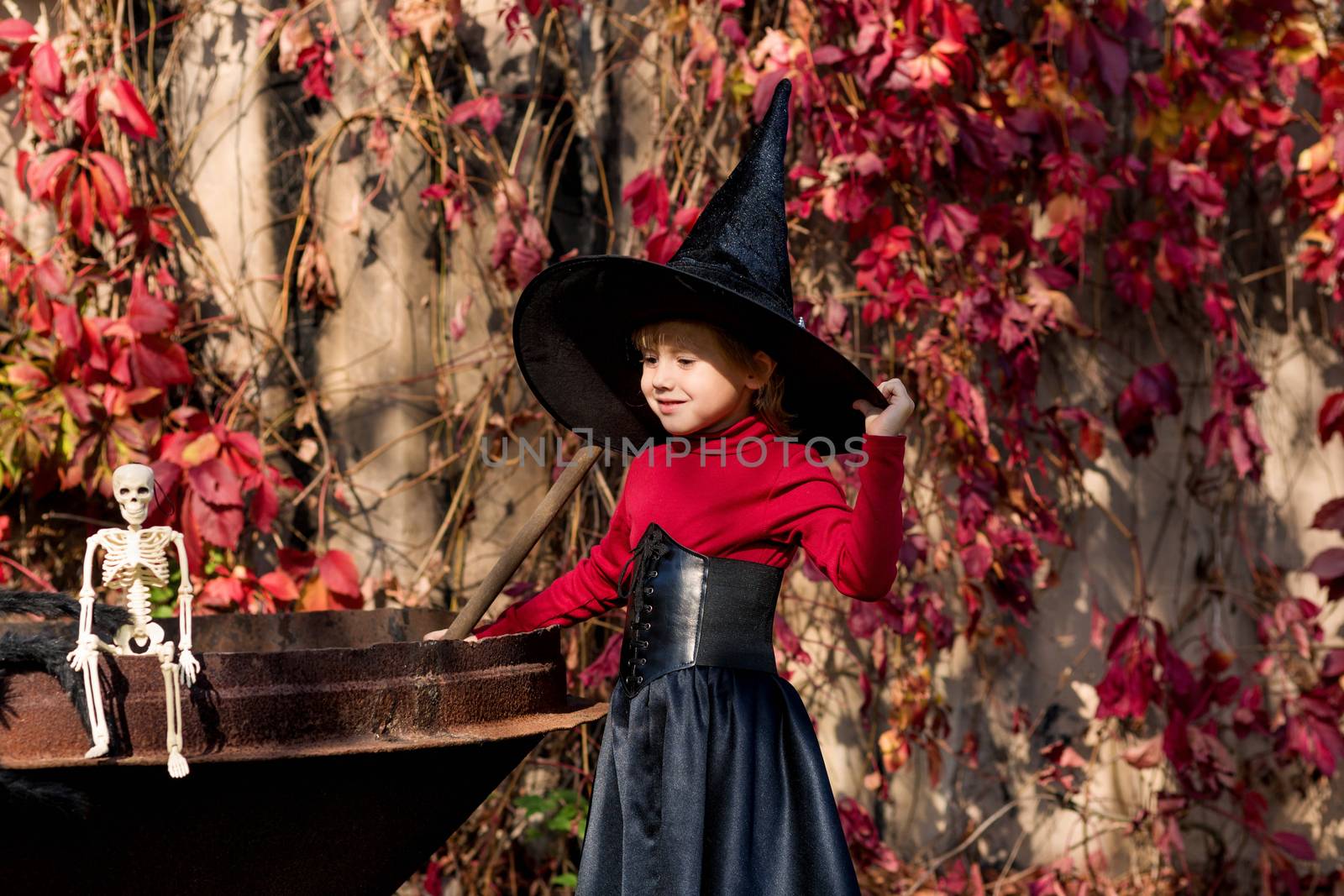 Little girl in a witch costume interferes with a potion on a halloween party by galinasharapova