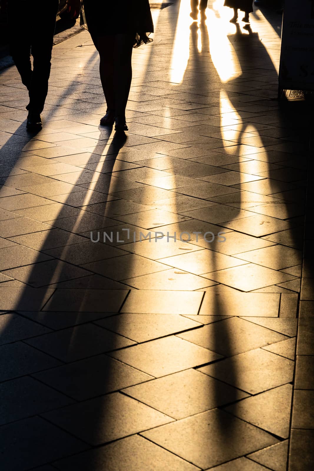 Backlight image of long shadows of people walking on the sidewalk. Captured just before sunset in Newtown, Sydney, Australia