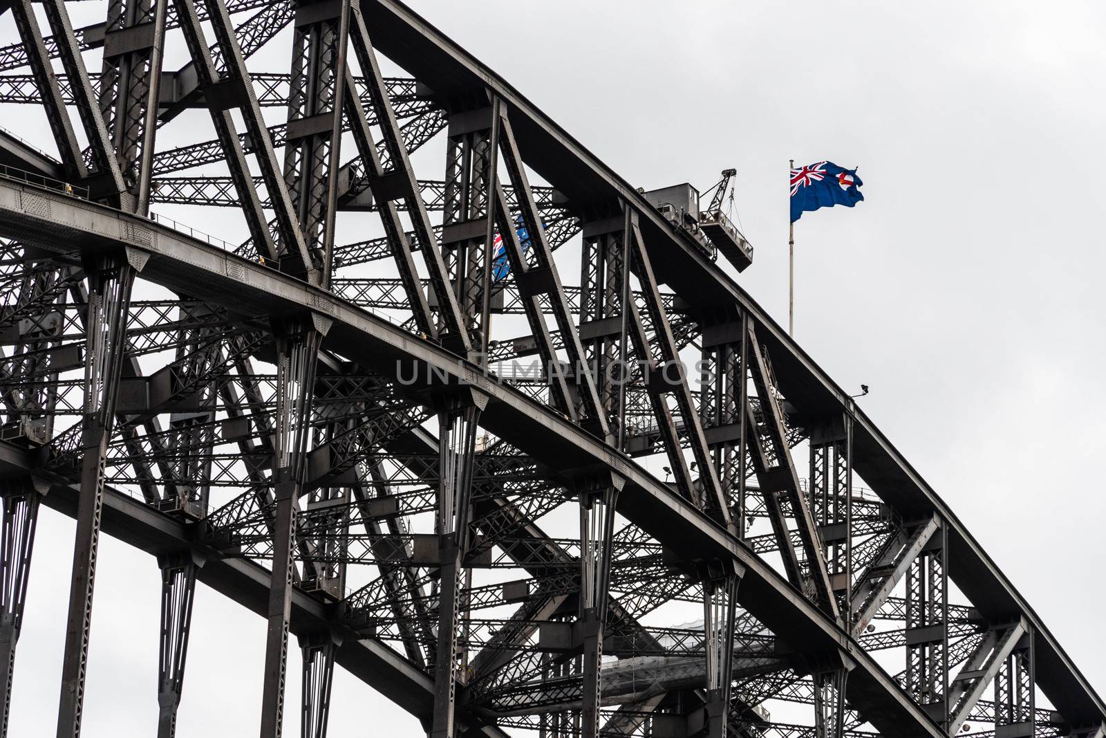 Close-up view of Harbour Bridge steel complex structure and the Australian flag on the top. Sydney, Australia