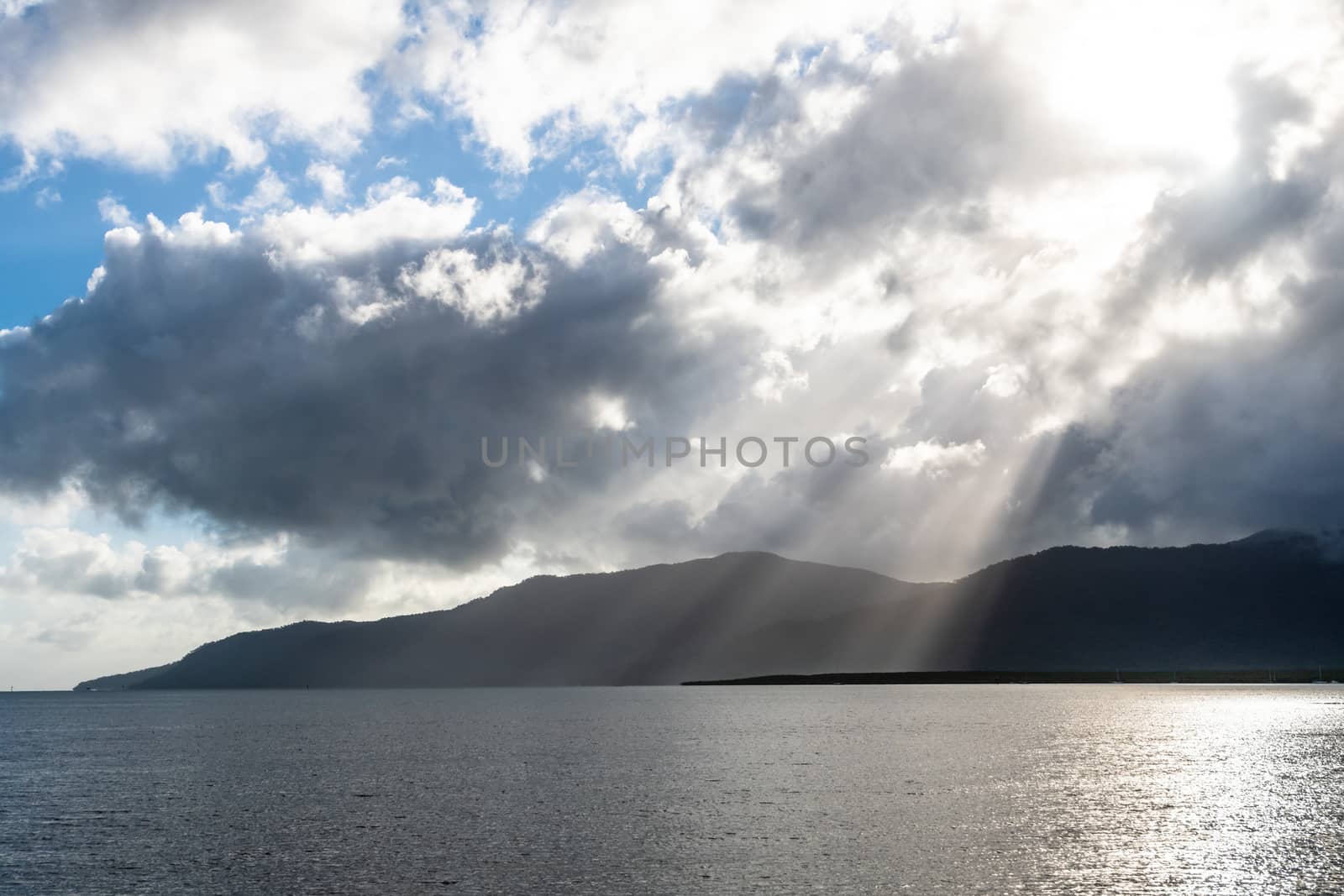 Backlight photo of morning sun-rays illuminating Cairns coastline through the clouds