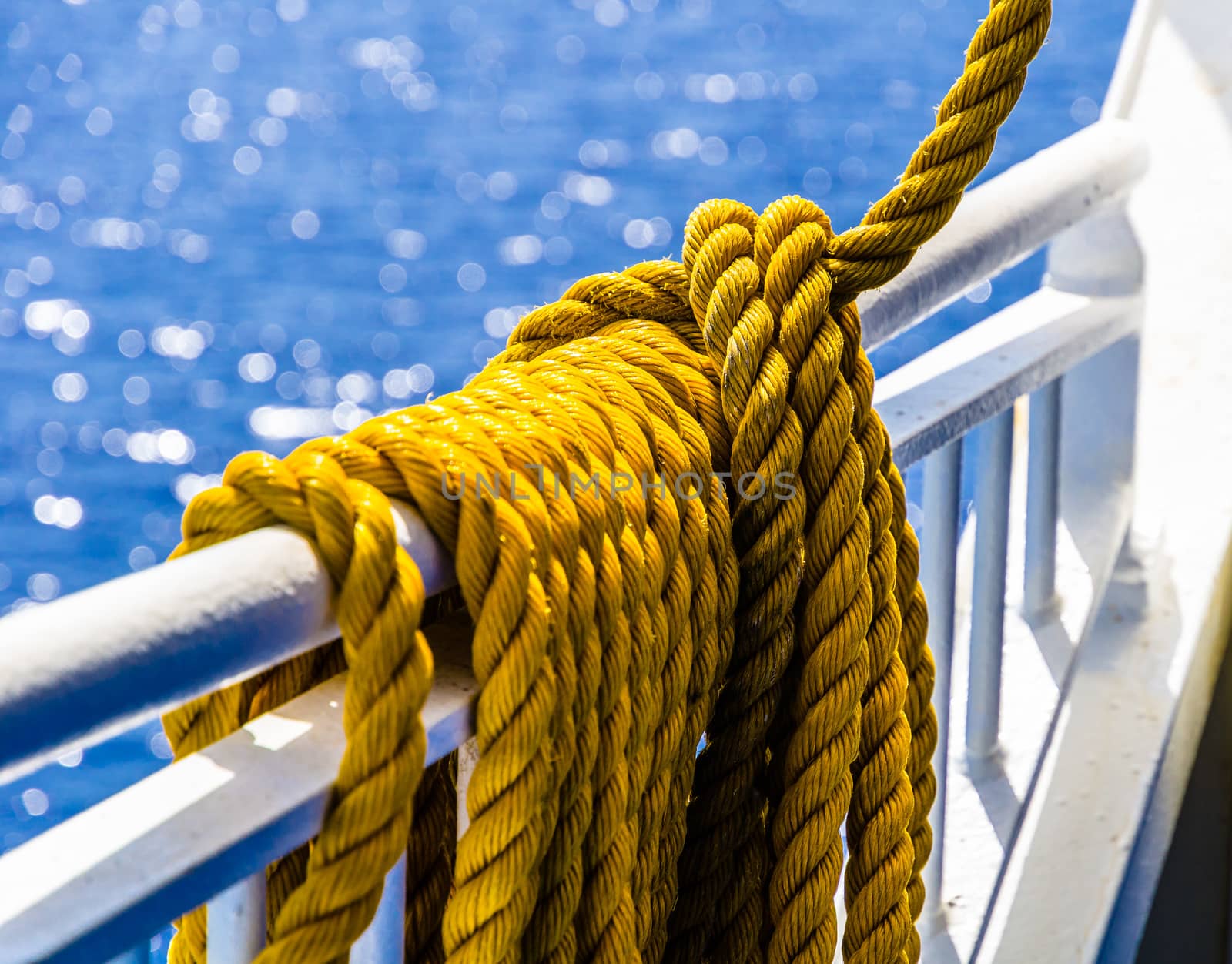 Close up of yellow braided rope draped over a ship railing