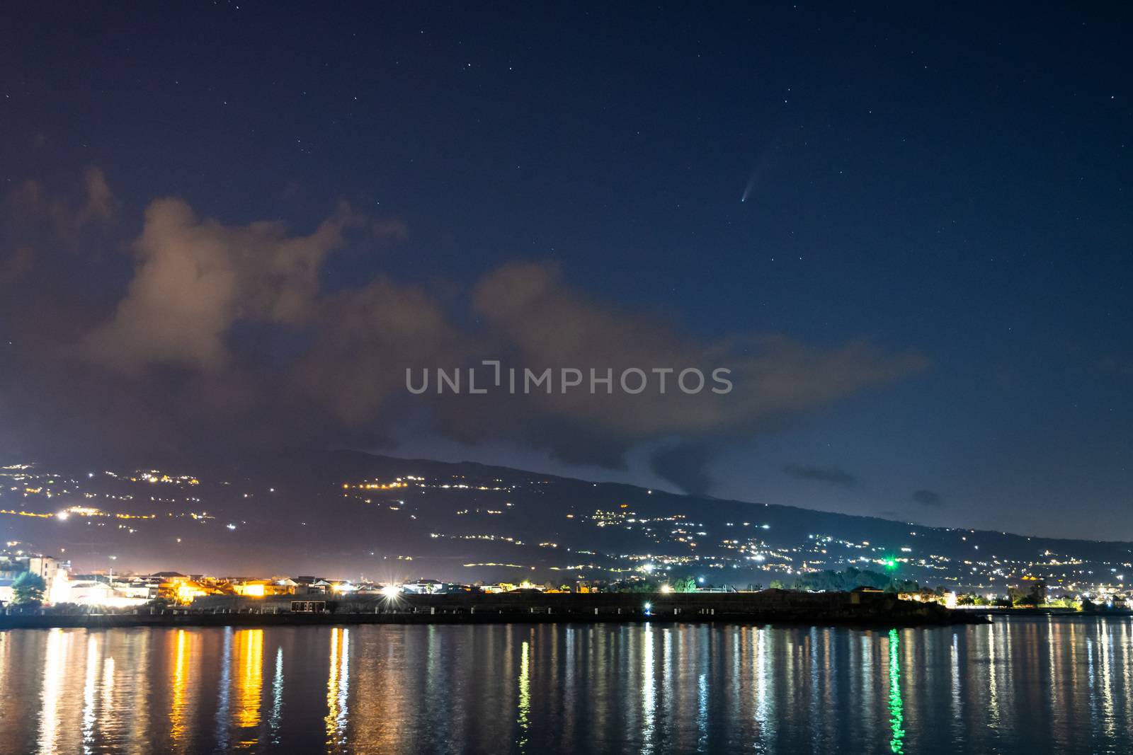Neowise Comet and its tail from illuminated Riposto harbour near Etna volcano, Sicily, Italy
