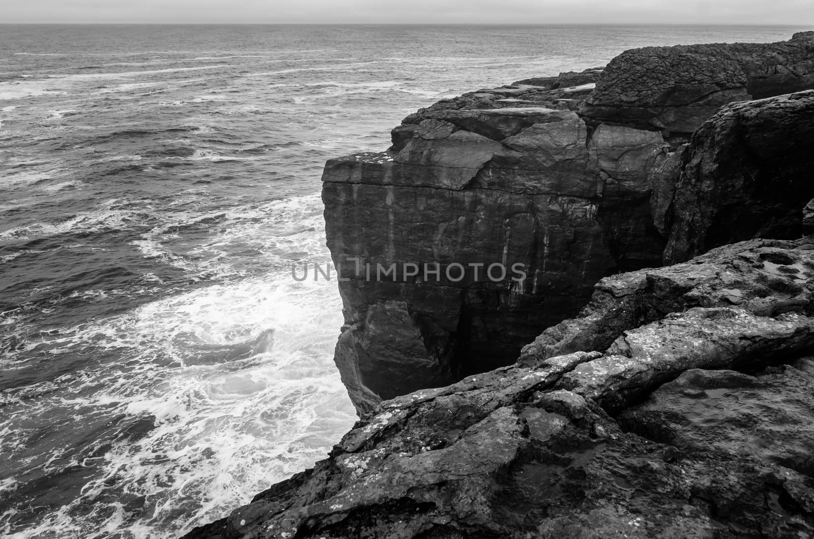 Black and white seascape of Irish cliffs battered by waves, Ireland by mauricallari