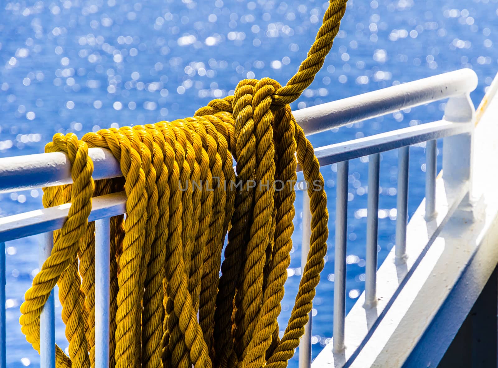 Close up of yellow braided rope draped over a ship railing