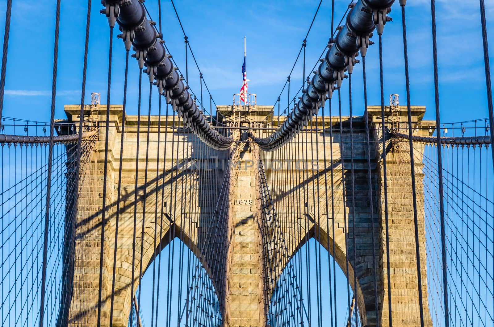 The web of cables of Brooklyn bridge in a sunny afternoon on a blue sky as background