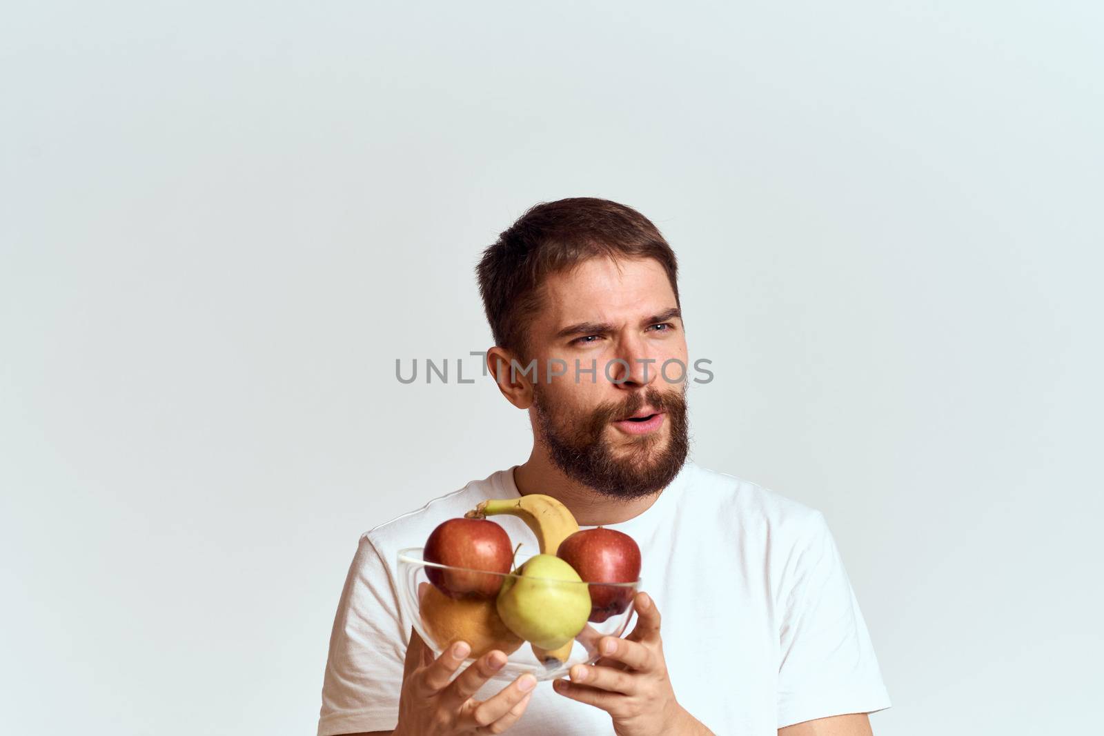 man with fresh fruit in a glass cup gesturing with hands vitamins health energy model bushy beard mustache. High quality photo