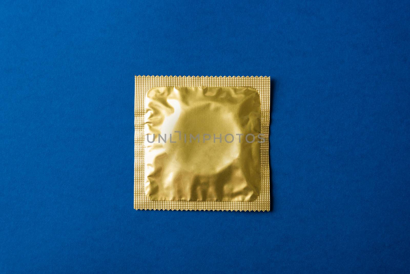 World sexual health or Aids day, Top view flat lay condom in wrapper pack, studio shot isolated on a dark blue background, Safe sex and reproductive health concept