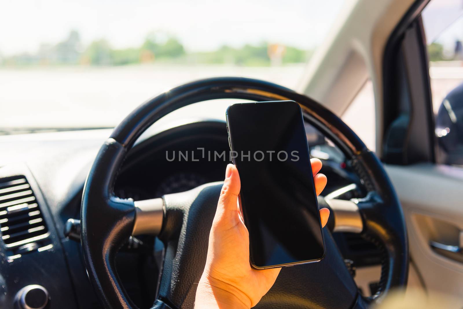 Asian woman inside a car and using a hand holding mobile smartphone blank screen while driving the car by Sorapop