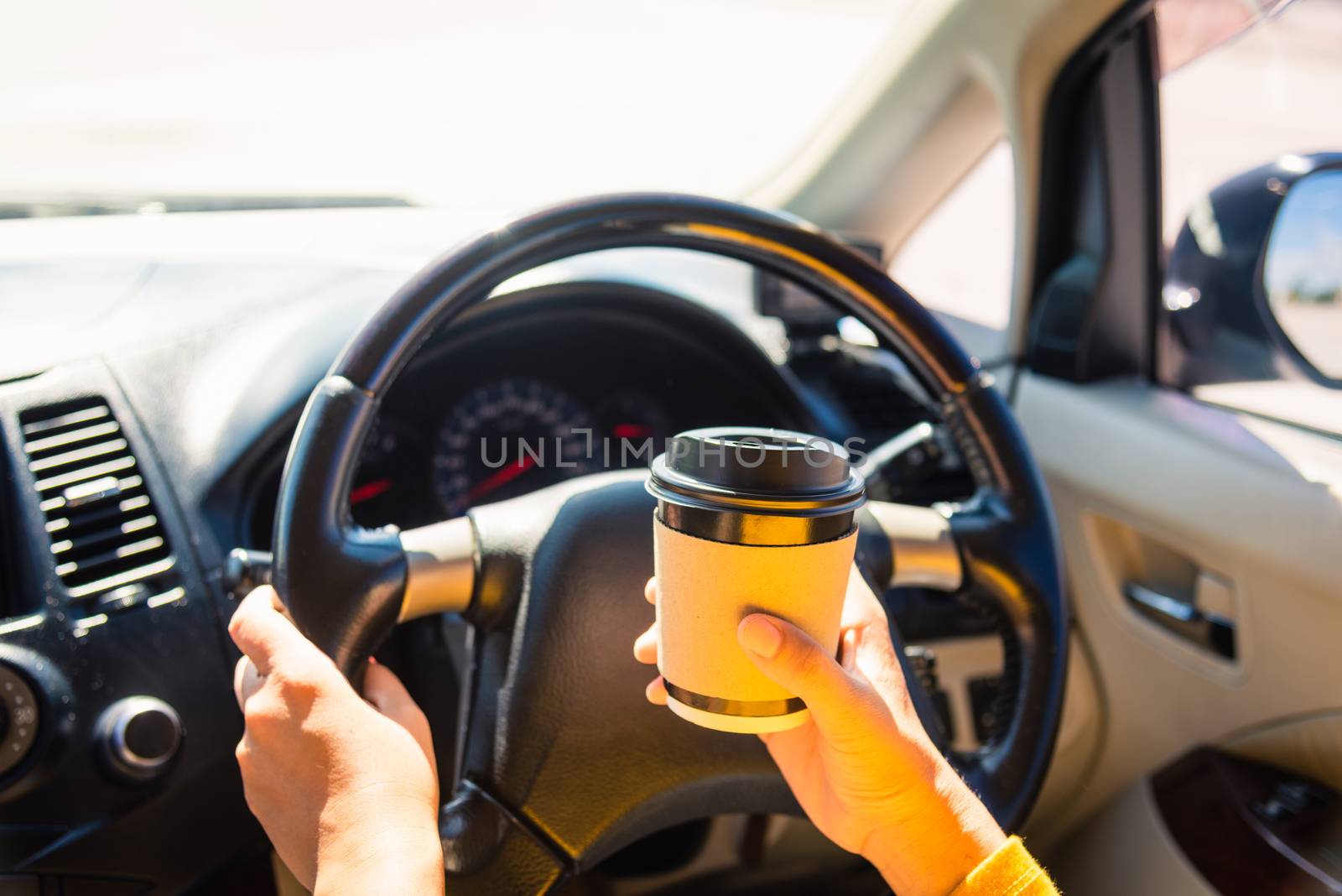 woman drinking hot coffee takeaway cup inside a car by Sorapop