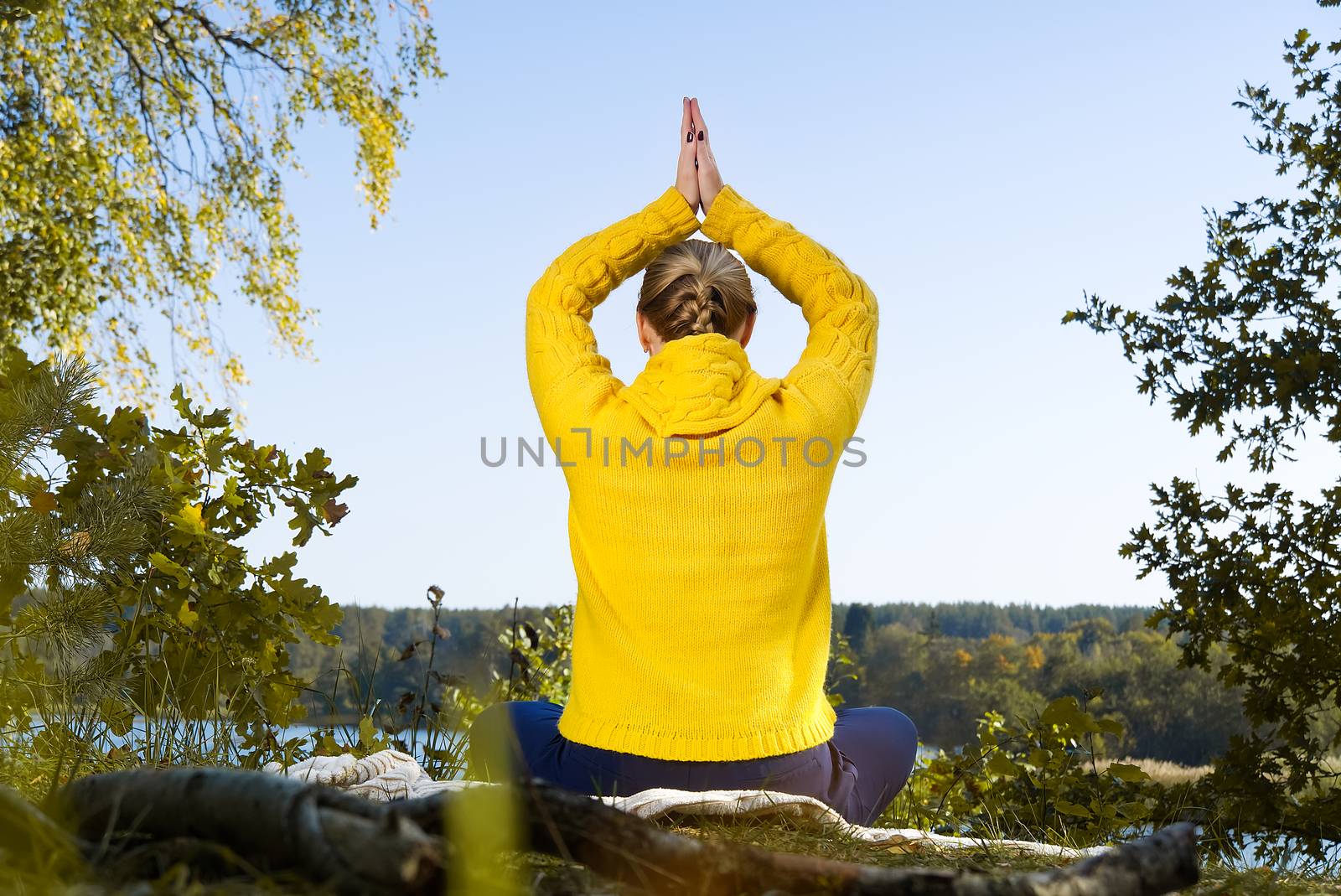 Beautiful young girl meditating in autumn park. woman meditates in the forest in sunny day. by PhotoTime
