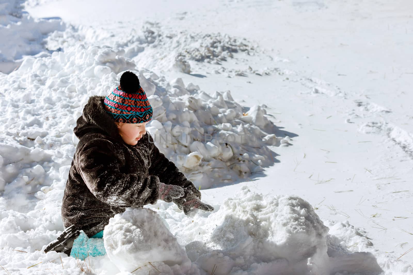 Beautiful happy little kid play with snow in a snow on home drive way