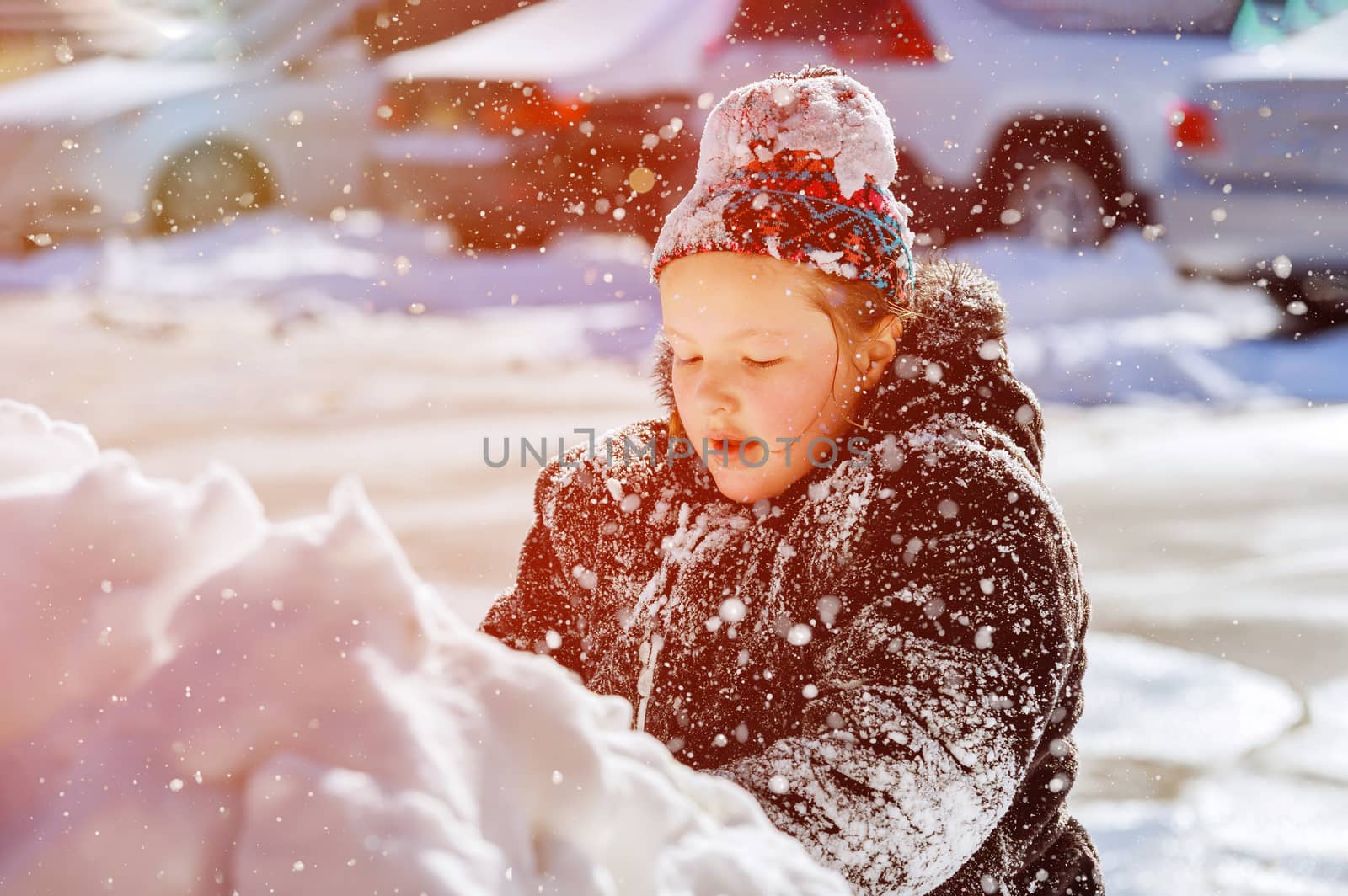 Girl child playing with snow in winter in the sunny day