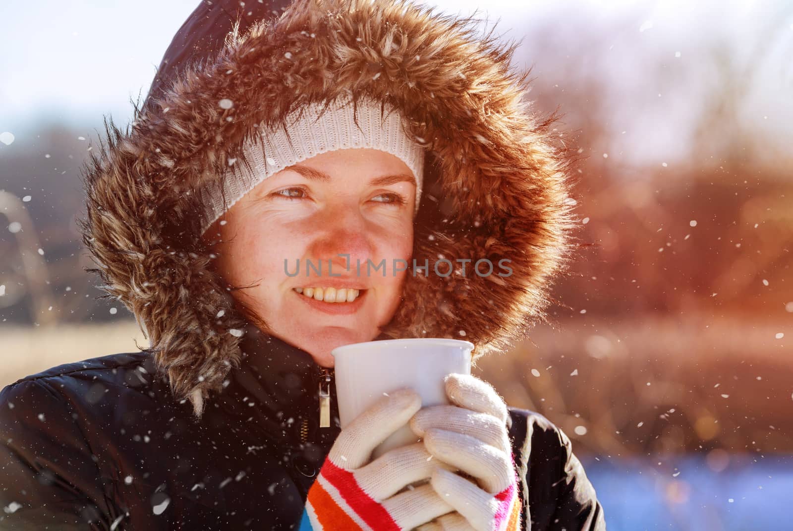 Woman walking in the street of wearing warm scarf and hat smiling and drinking hot tea