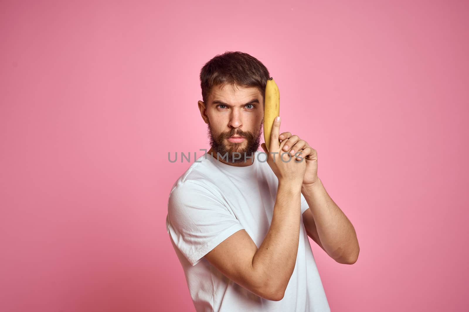 bearded man with banana in hand on pink background fun emotions model by SHOTPRIME