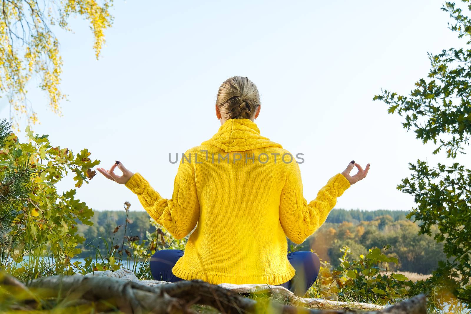 Beautiful young girl meditating in autumn park. woman meditates in the forest in sunny day. by PhotoTime