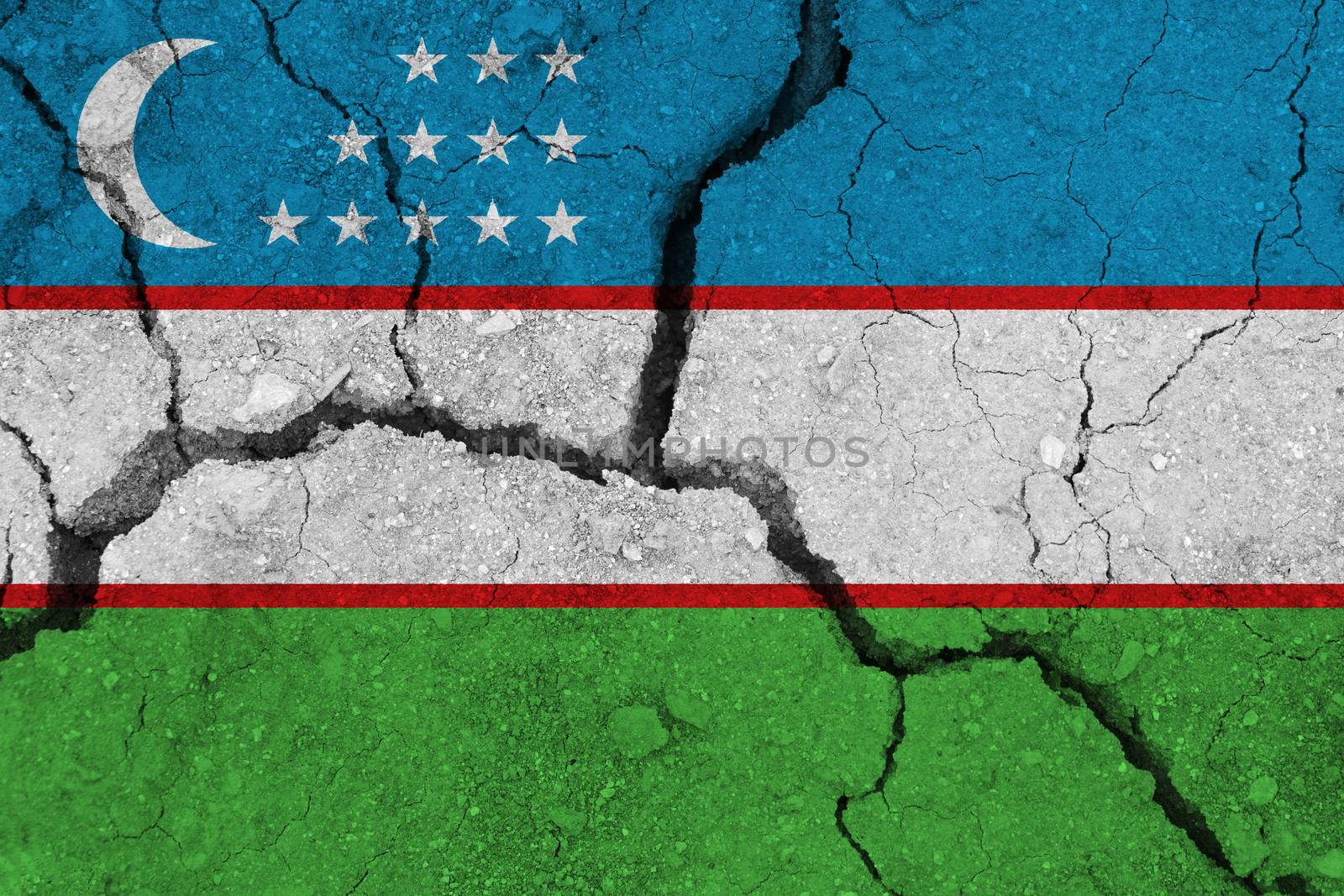 Uzbekistan flag on the cracked earth. National flag of Uzbekistan. Earthquake or drought concept
