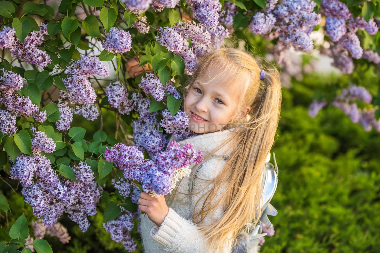 Little girl smelling lilac flowers in sunny day. by infinityyy