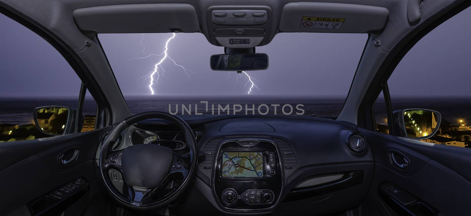 Car windshield with lightning storm over the sea by marcorubino