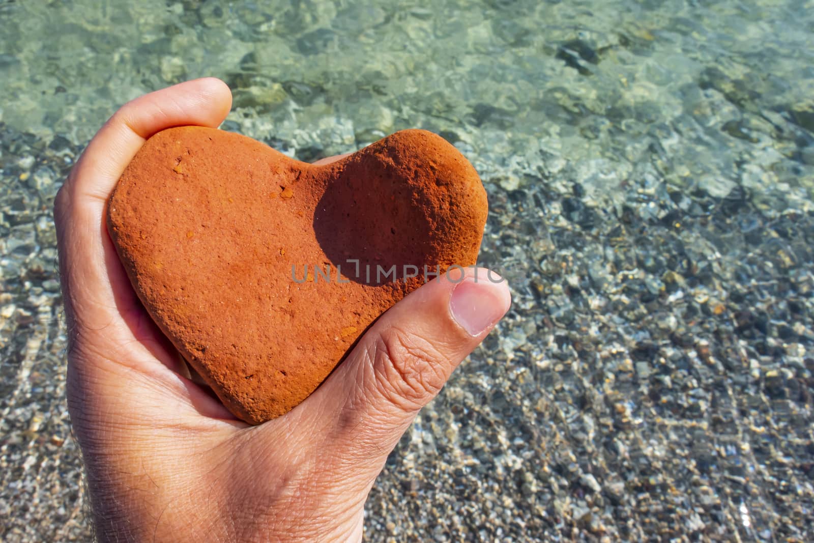 orange heart shaped stone at the beach