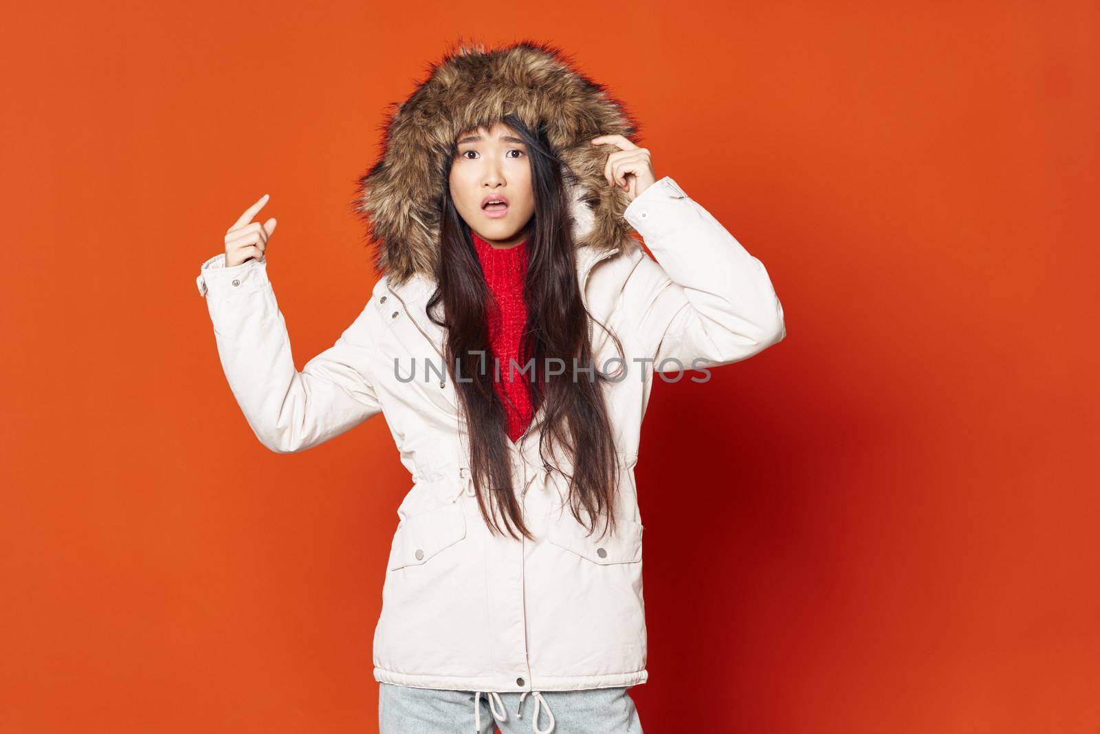woman shows a finger on a hood and a red background, model