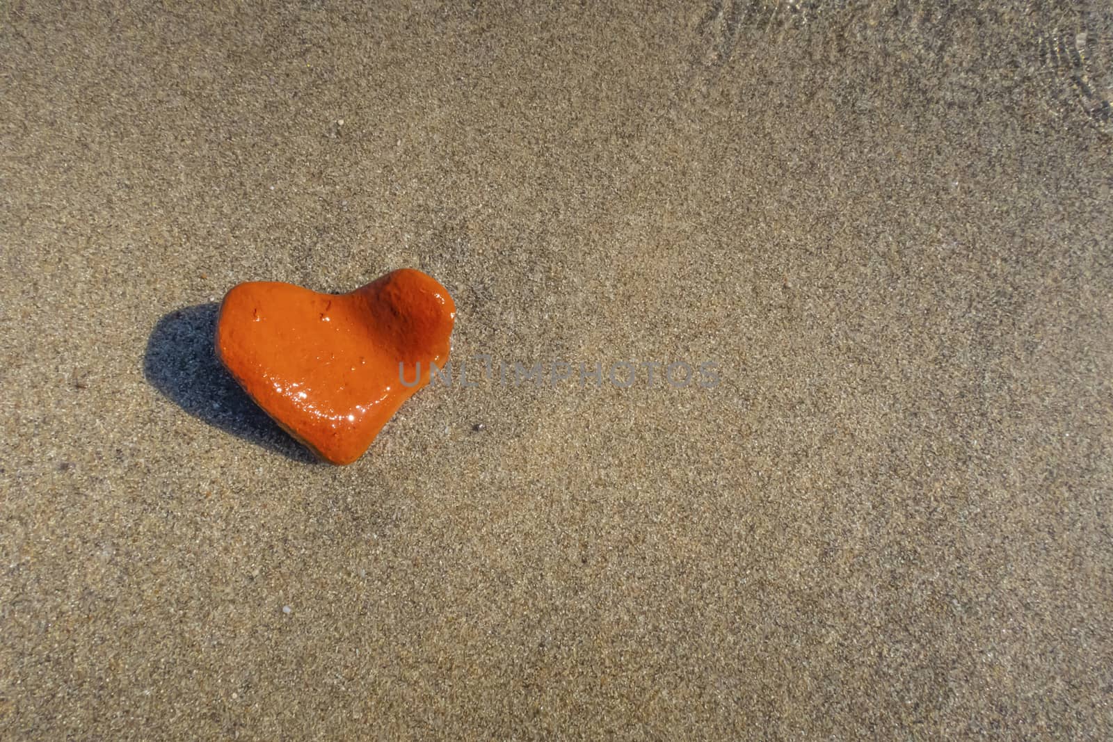 orange heart shaped stone at the beach