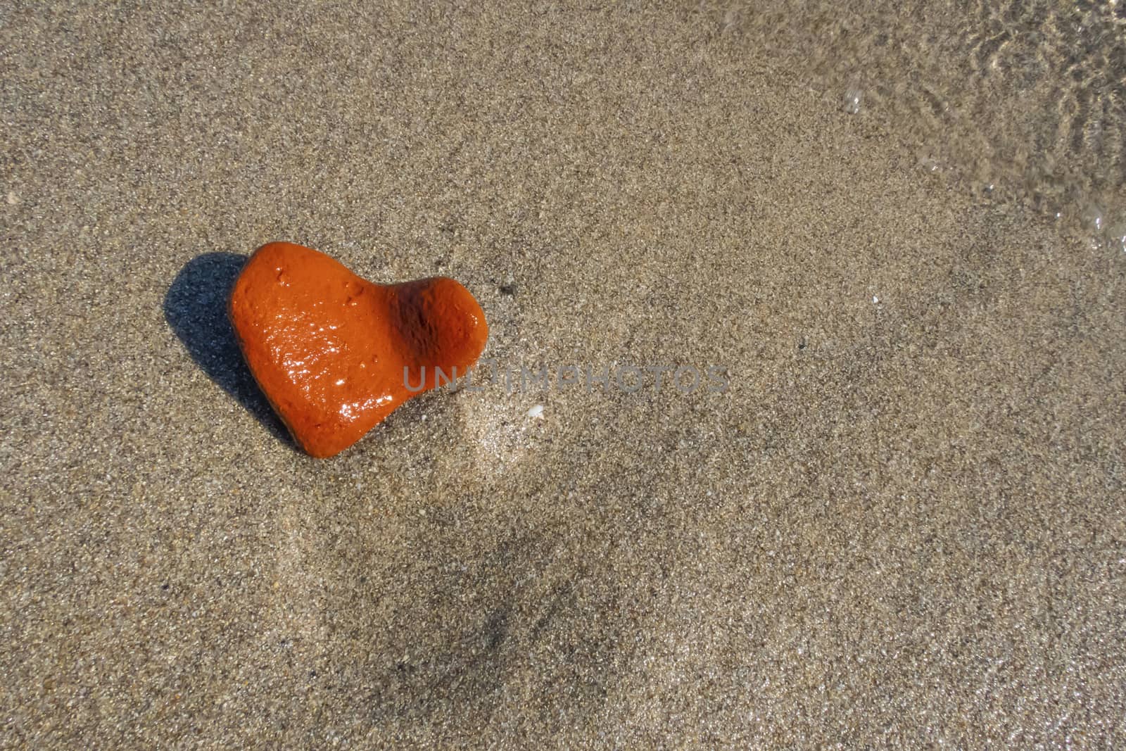 orange heart shaped stone at the beach