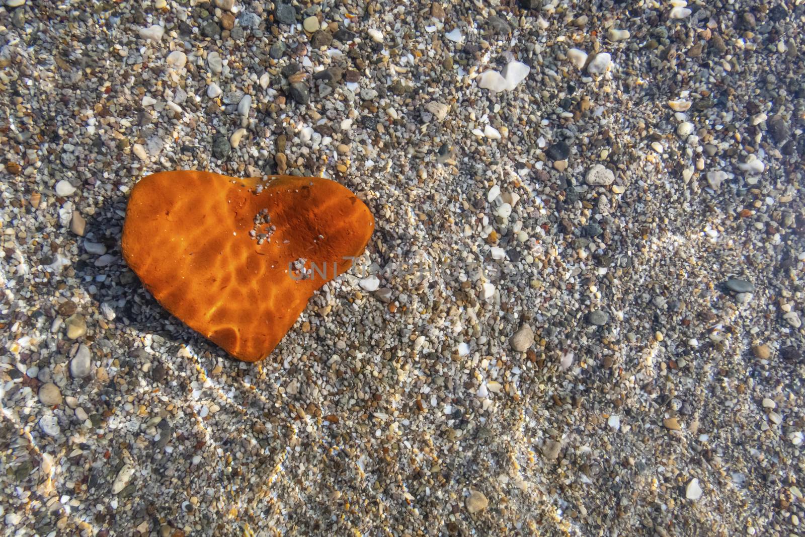 orange heart shaped stone at the beach