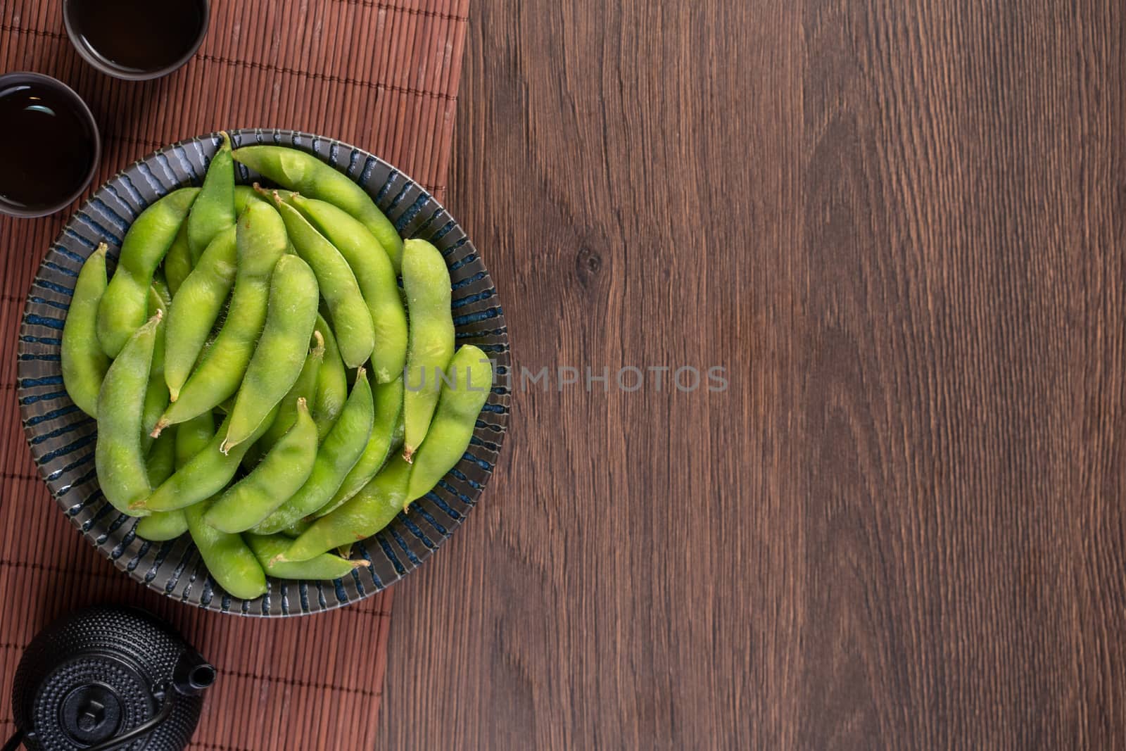 Top view of fresh cooked boiled edamame in a plate on wooden tray and table background with copy space, healthy protein food concept.