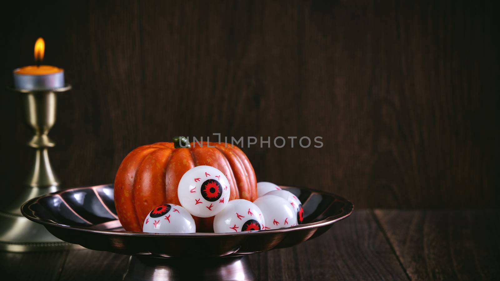 Close up of spooky Halloween tricks, concept of horror festival decor, pumpkin lantern with candlestick and smoke.