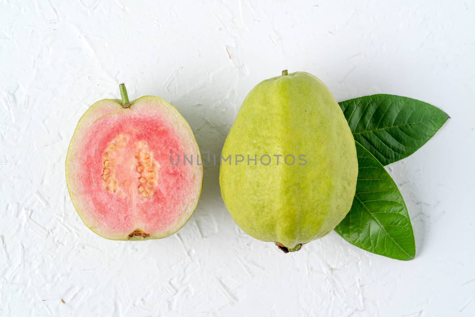 Top view, flat lay of delicious beautiful Red guava with fresh green leaves isolated on white table background, studio overhead table shot with copy space.
