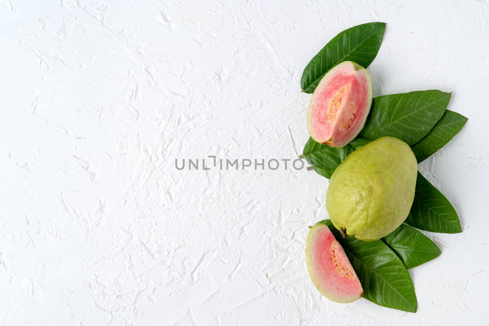 Top view, flat lay of delicious beautiful Red guava with fresh green leaves isolated on white table background, studio overhead table shot with copy space.
