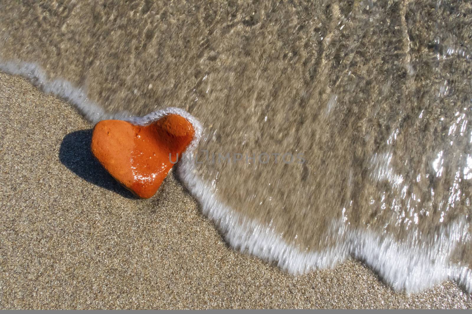 orange heart shaped stone at the beach