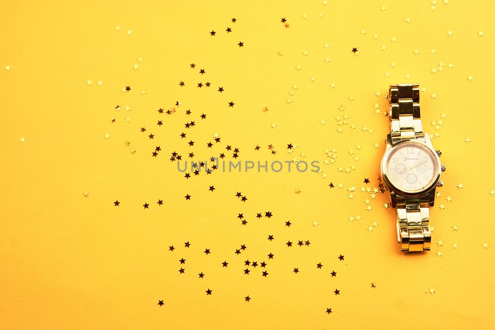 Wristwatch on yellow background and Copy Space glitter. High quality photo
