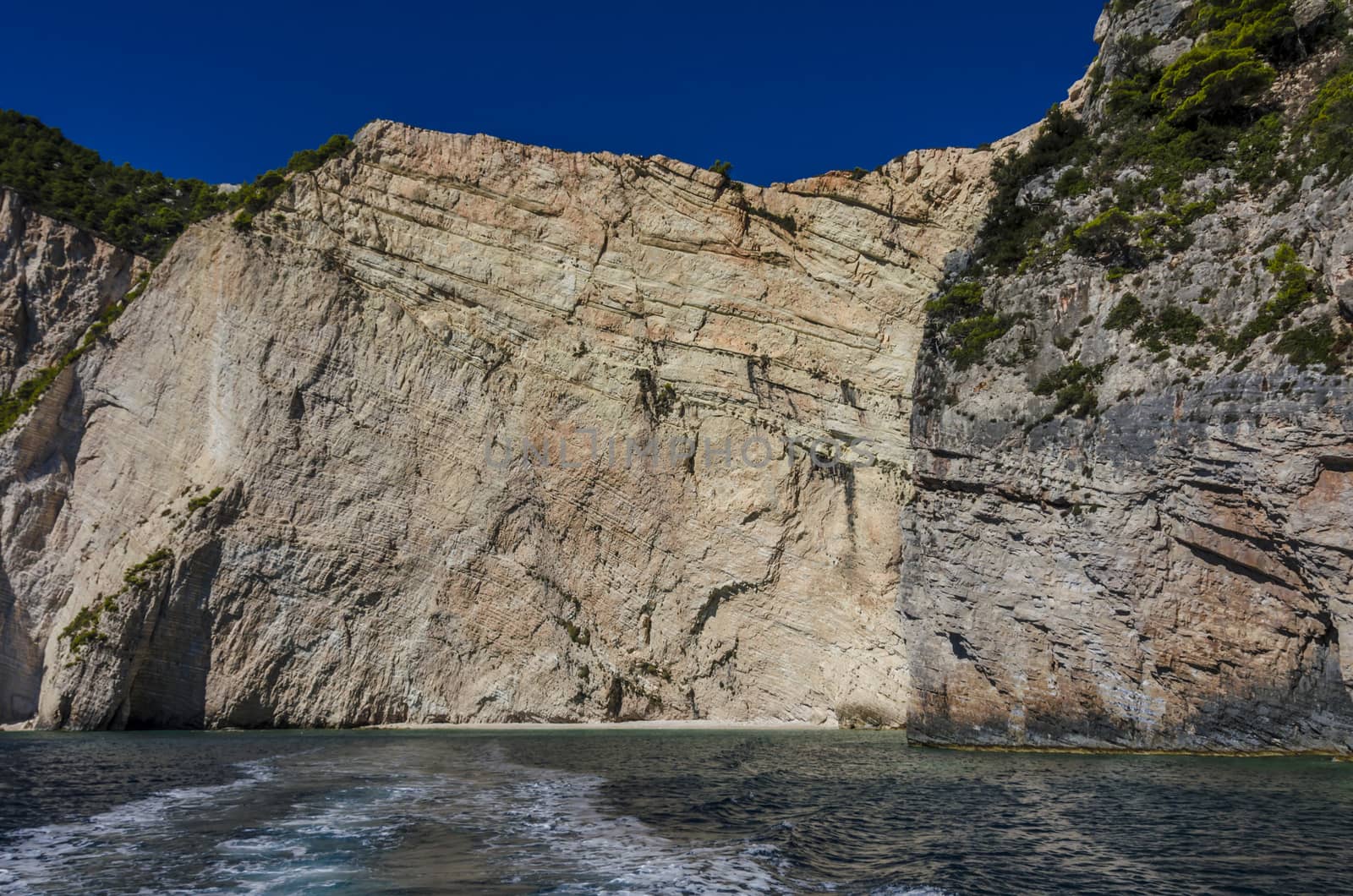 you can see the different layers of formation on the rock walls of the reefs and at sea level a sandy and rocks beach