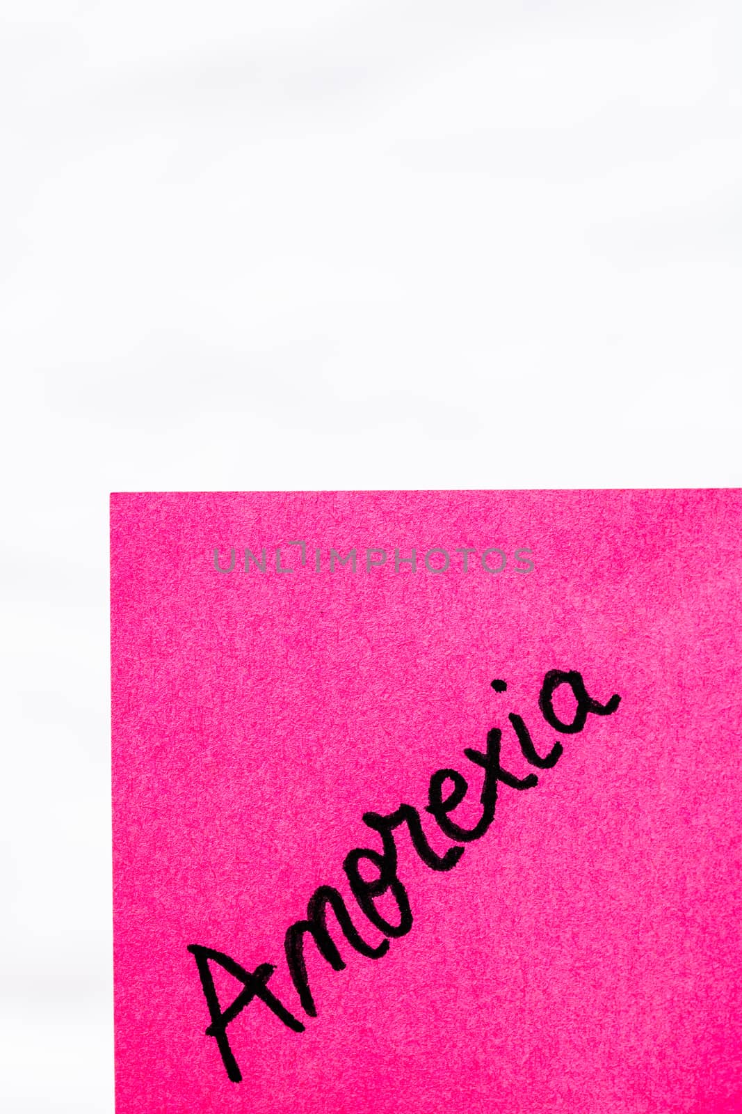 Anorexia handwriting text close up isolated on pink paper with copy space. Writing text on memo post reminder