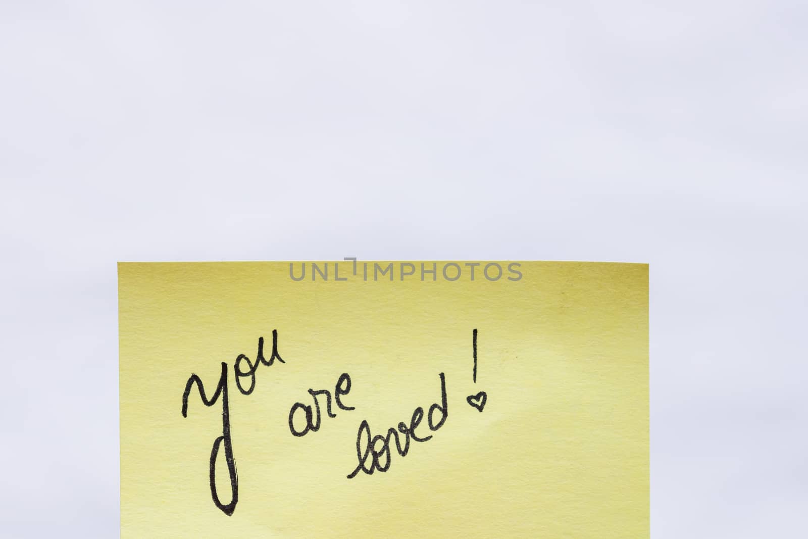 You are loved handwriting text close up isolated on yellow paper with copy space.