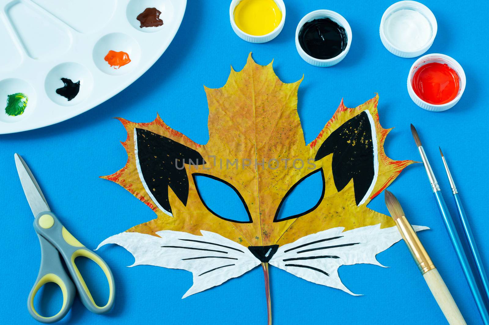 Mask painted on maple leaf. Drawing on autumn leaves. Fox mask for autumn carnival or party. Art project for children. DIY concept